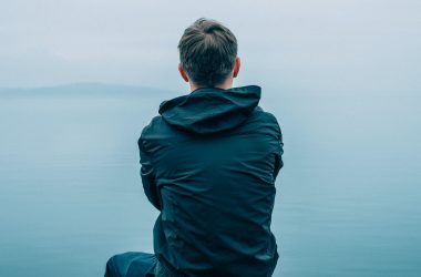 Sad guy sitting at water's edge